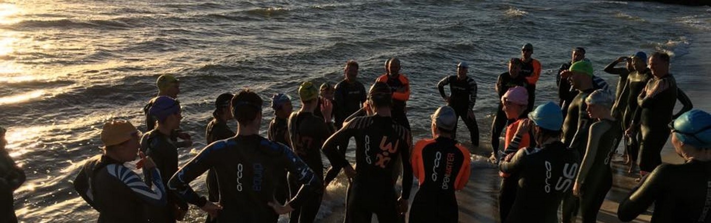 A large group of Tri Alliance beginner triathletes gathering for open-water coaching