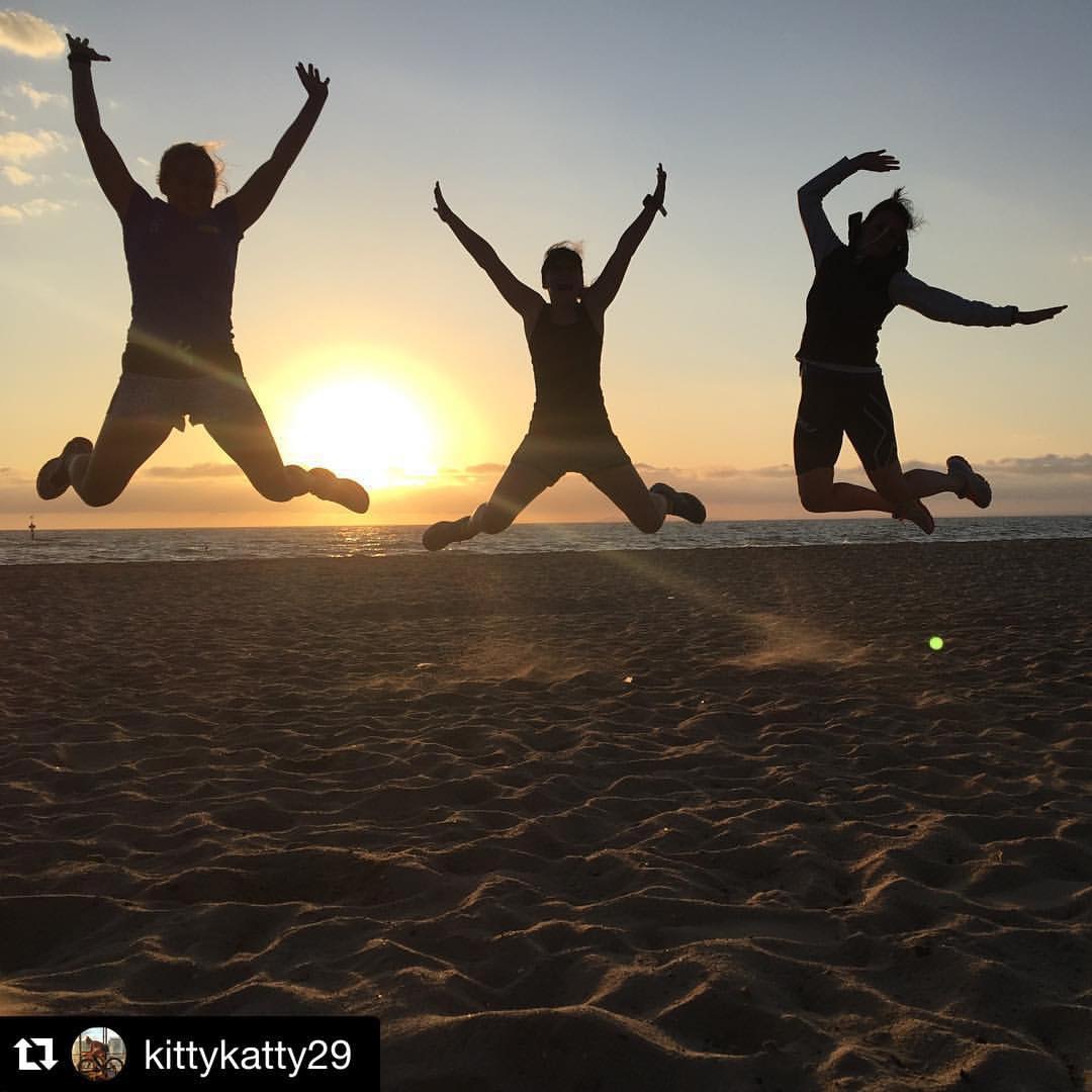 Four people jumping together in silhouette on a beach at sunrise