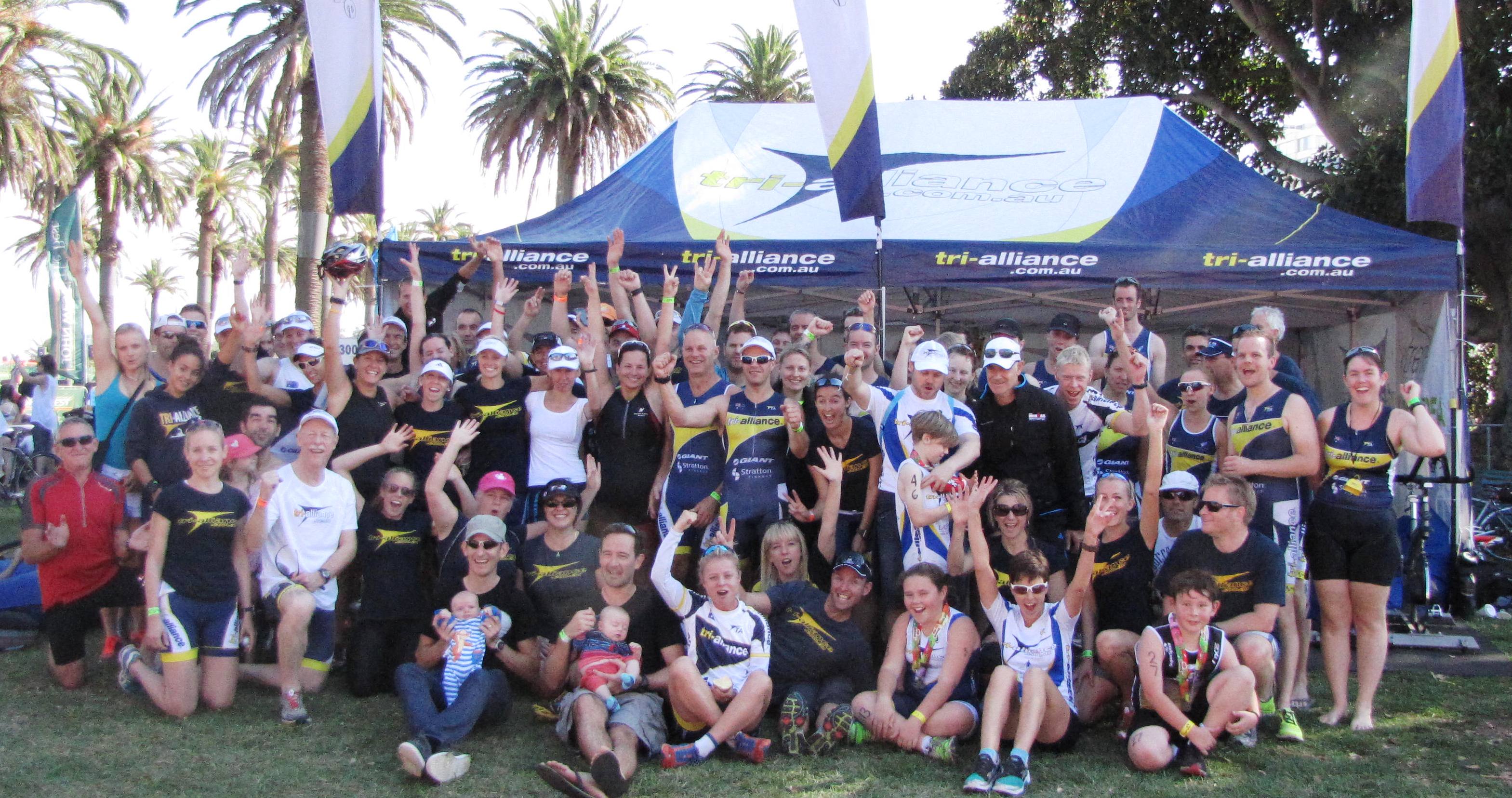 A large Tri Alliance race-day squad gathered beneath team tents