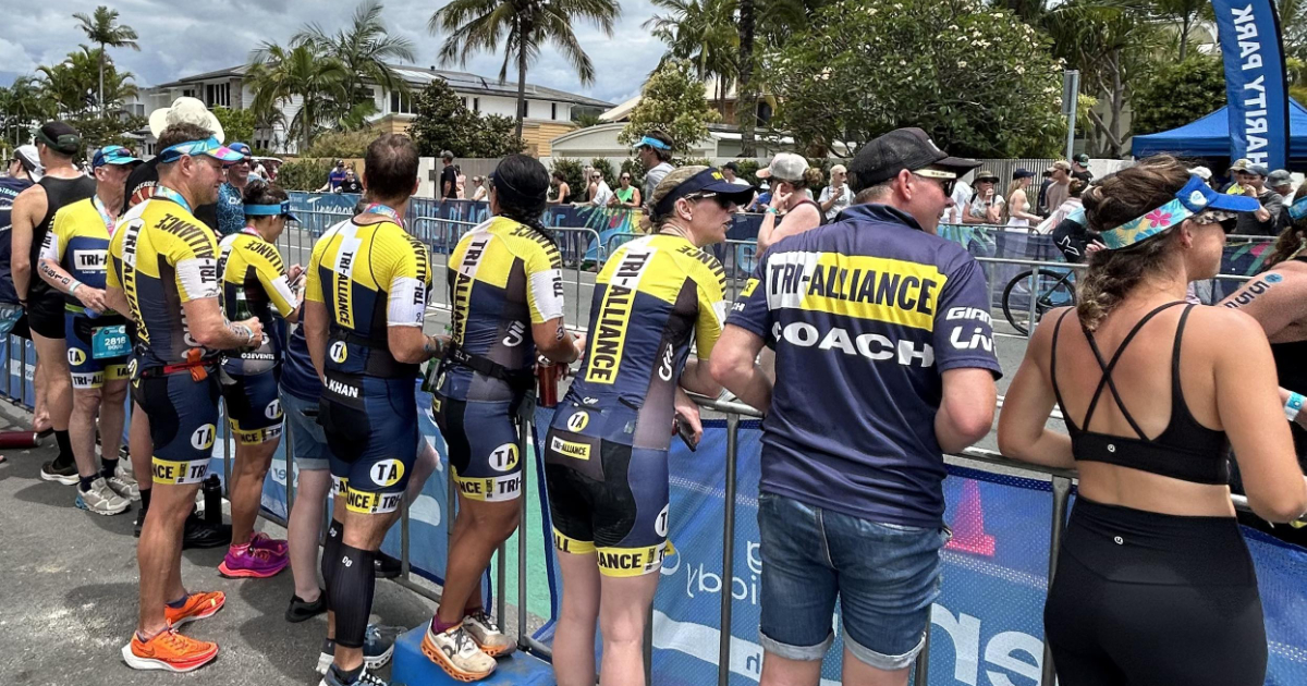 Tri Alliance athletes and a coach standing together beside a race course in Noosa