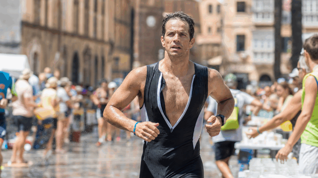 Triathlete running through aid stations in hot race conditions