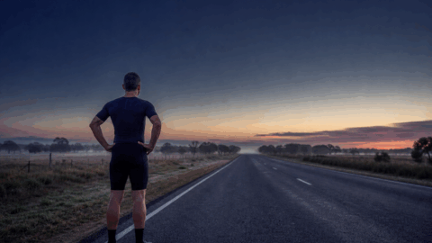 A lone triathlete training on an empty road at dawn, symbolising the work still required before race day