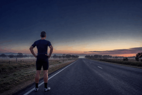 A lone triathlete training on an empty road at dawn, symbolising the work still required before race day