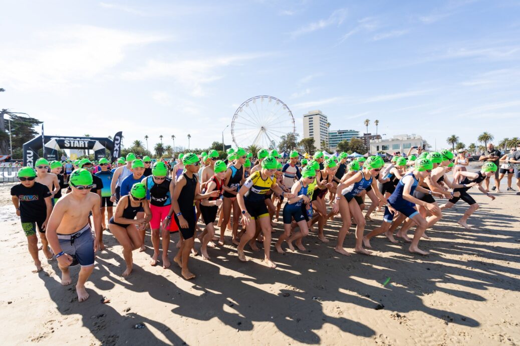 Swimmers with green caps preparing for a beach race start