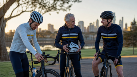 Three triathletes preparing their bikes together before a training ride