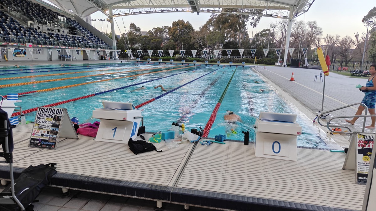 Tri Alliance Monday evening squad swim in the MSAC outdoor 50 m pool, swimmers in the lanes and the Triathlon Training sign on the pool deck