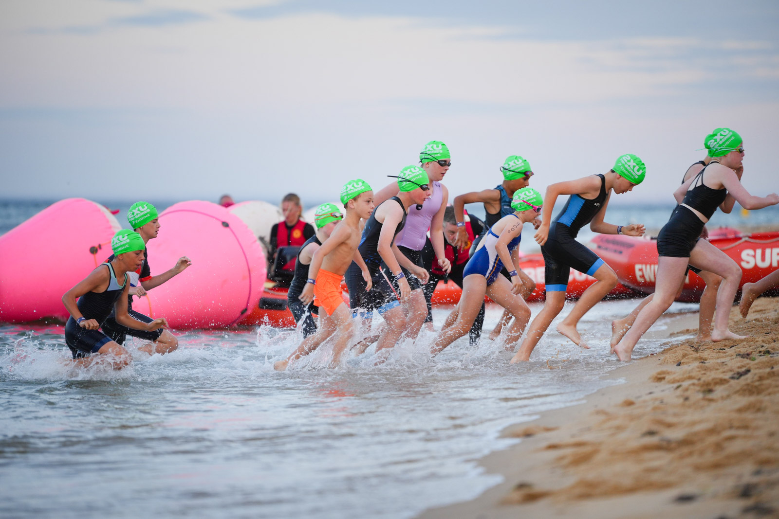 Young swimmers entering the ocean during a beach triathlon.