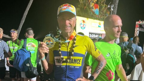 Mario Staffieri in Tri Alliance kit holding up his Ironman World Championship finisher medal in Kona