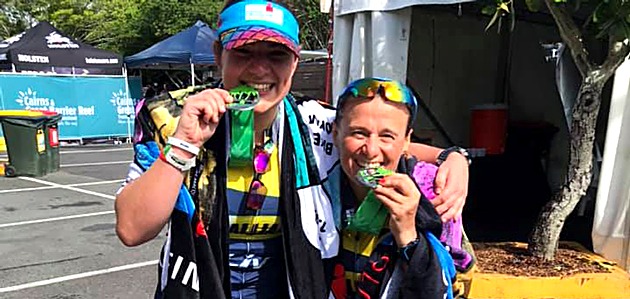 Two Tri Alliance women biting their finisher medals at Ironman 70.3 Cairns
